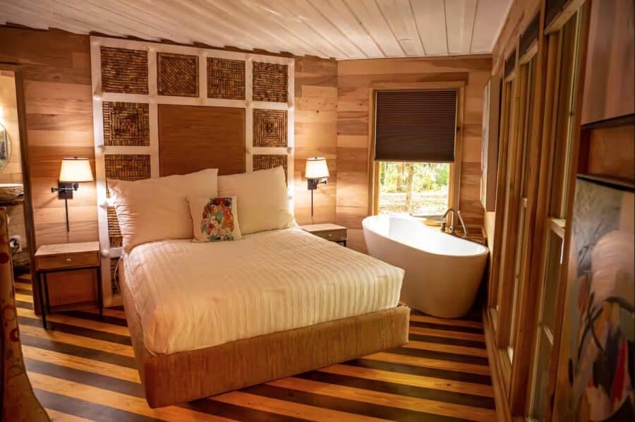 Charming cabin bedroom with warm wood interiors and a relaxing bathtub in Mentone, Alabama. Perfect.