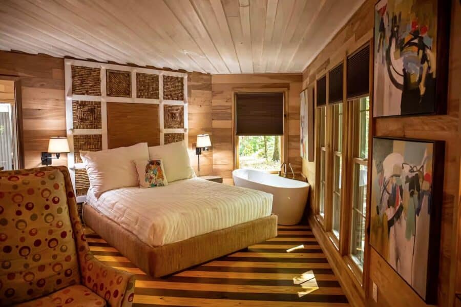 Comfortable bedroom in a rustic cabin with wooden walls and large windows.