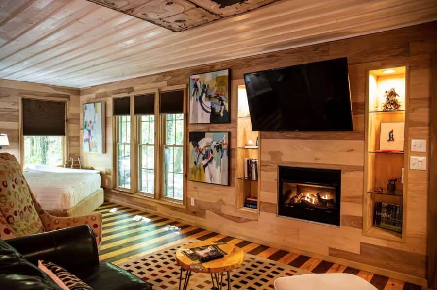 Charming cabin interior with a warm fireplace, colorful artwork, and large windows in Mentone, Alaba.