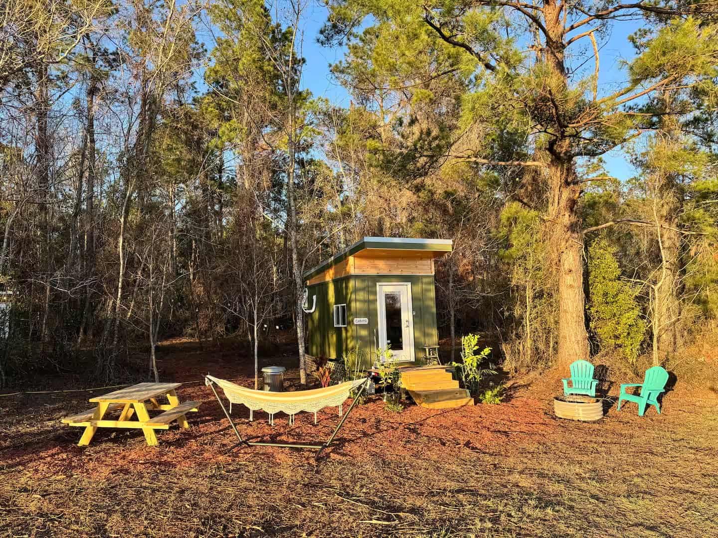 Mantra glamping cabin with a hammock strung between trees and a picnic table in golden evening light