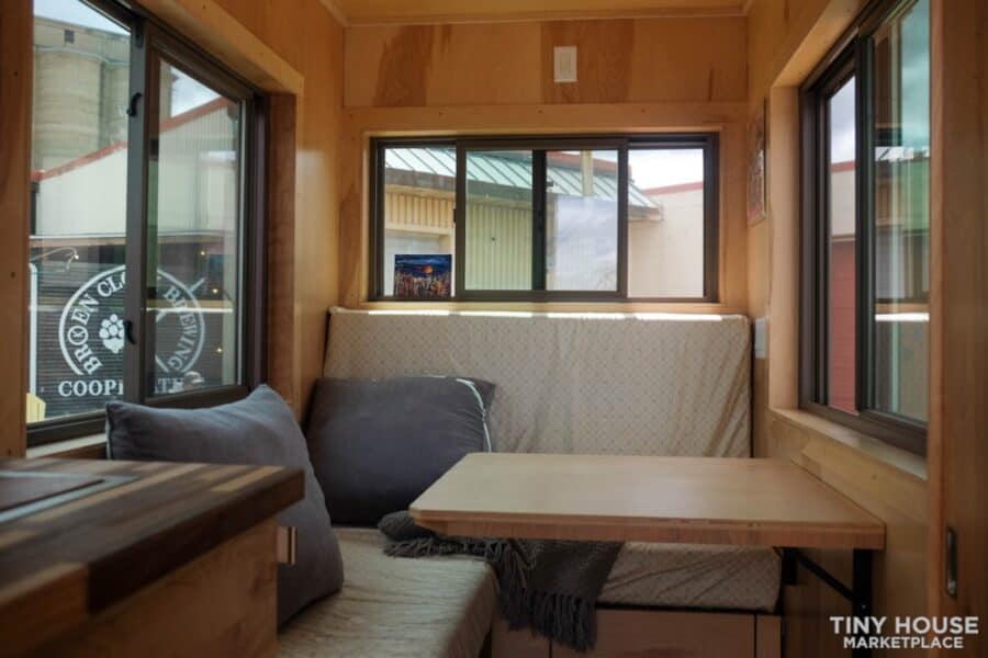 Small tiny house interior with cozy seating and large windows for natural light.