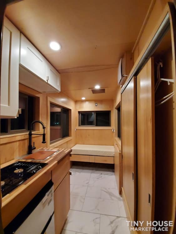 Compact tiny house kitchen with modern appliances and wood accents.