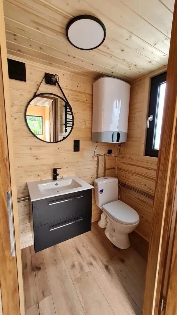 Mini bathroom with a vanity, toilet, water heater, and a window