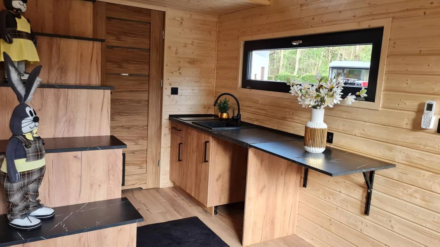 Kitchen in the Mini with wood cabinetry, a black countertop, a sink, and a fold-down bar counter