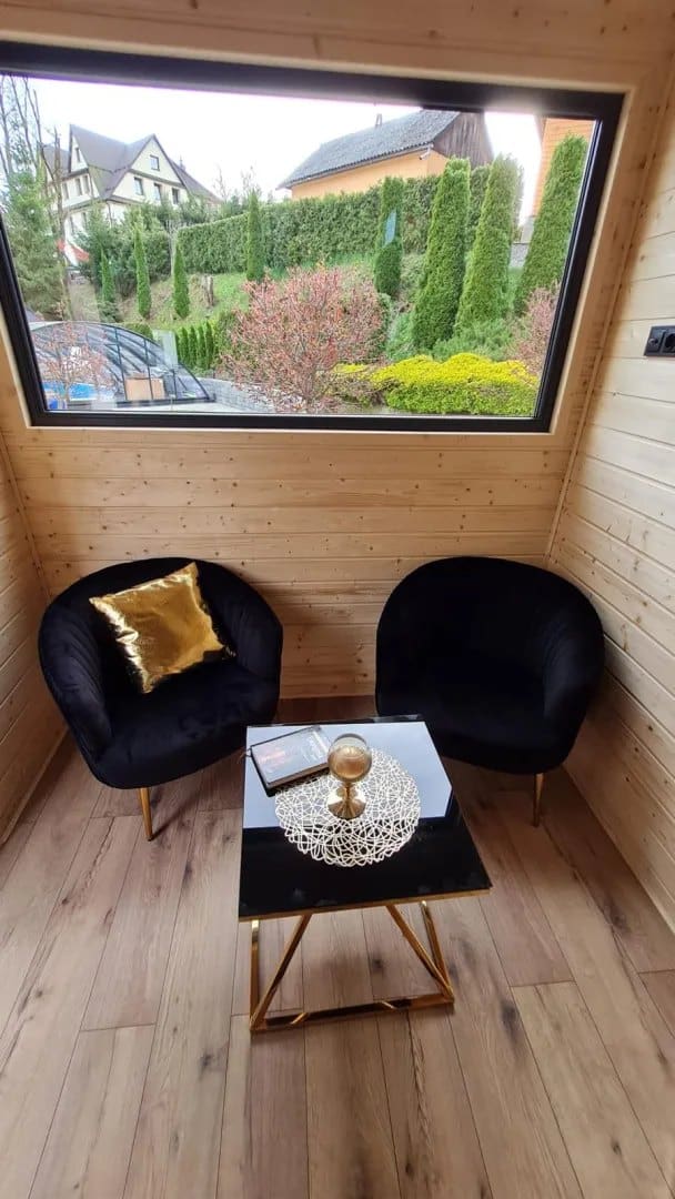 Living nook in the Mini with black velvet armchairs, a gold-and-glass table, and a garden-view window
