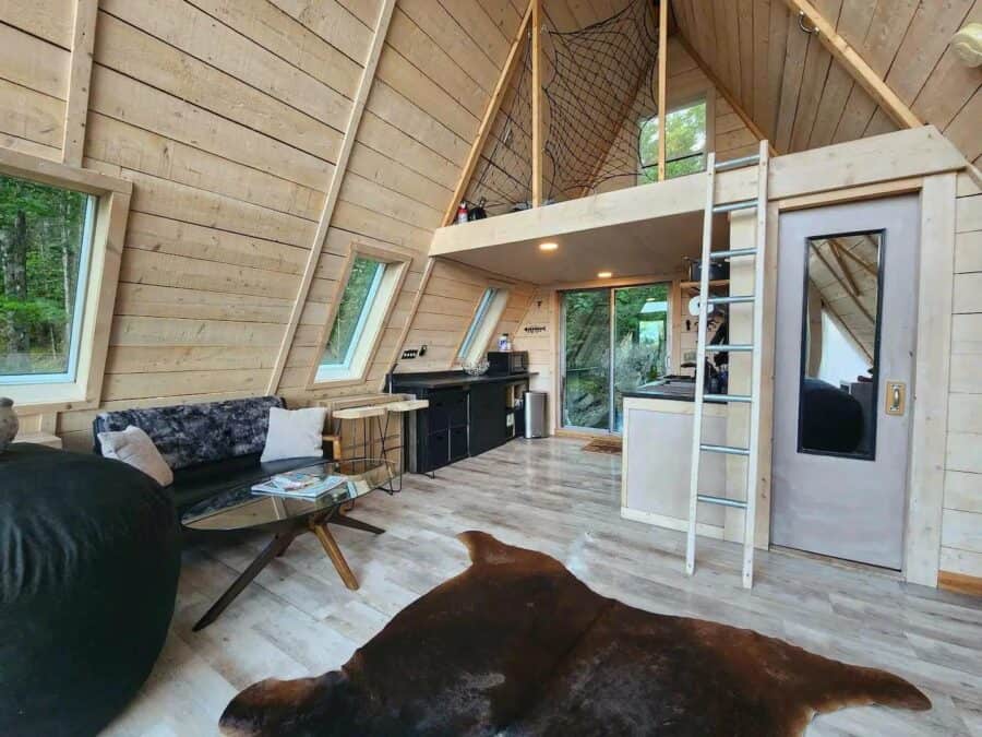 A-Frame tiny house interior featuring a cozy living area, loft space, and large windows with natural.