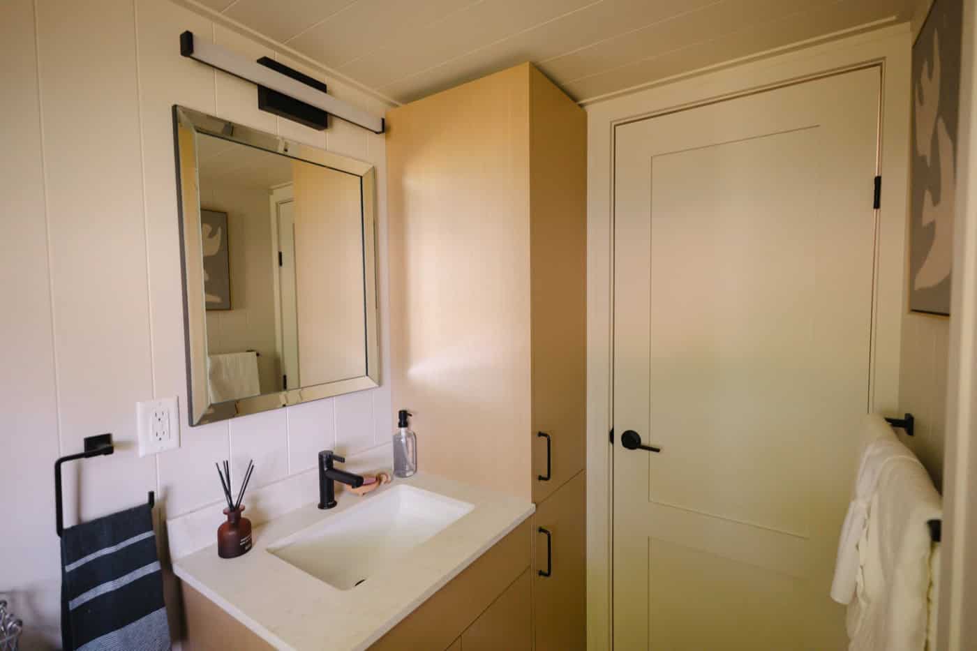Vanity with undermount sink, framed mirror, and full-height linen tower in the Mint Ventura bathroom