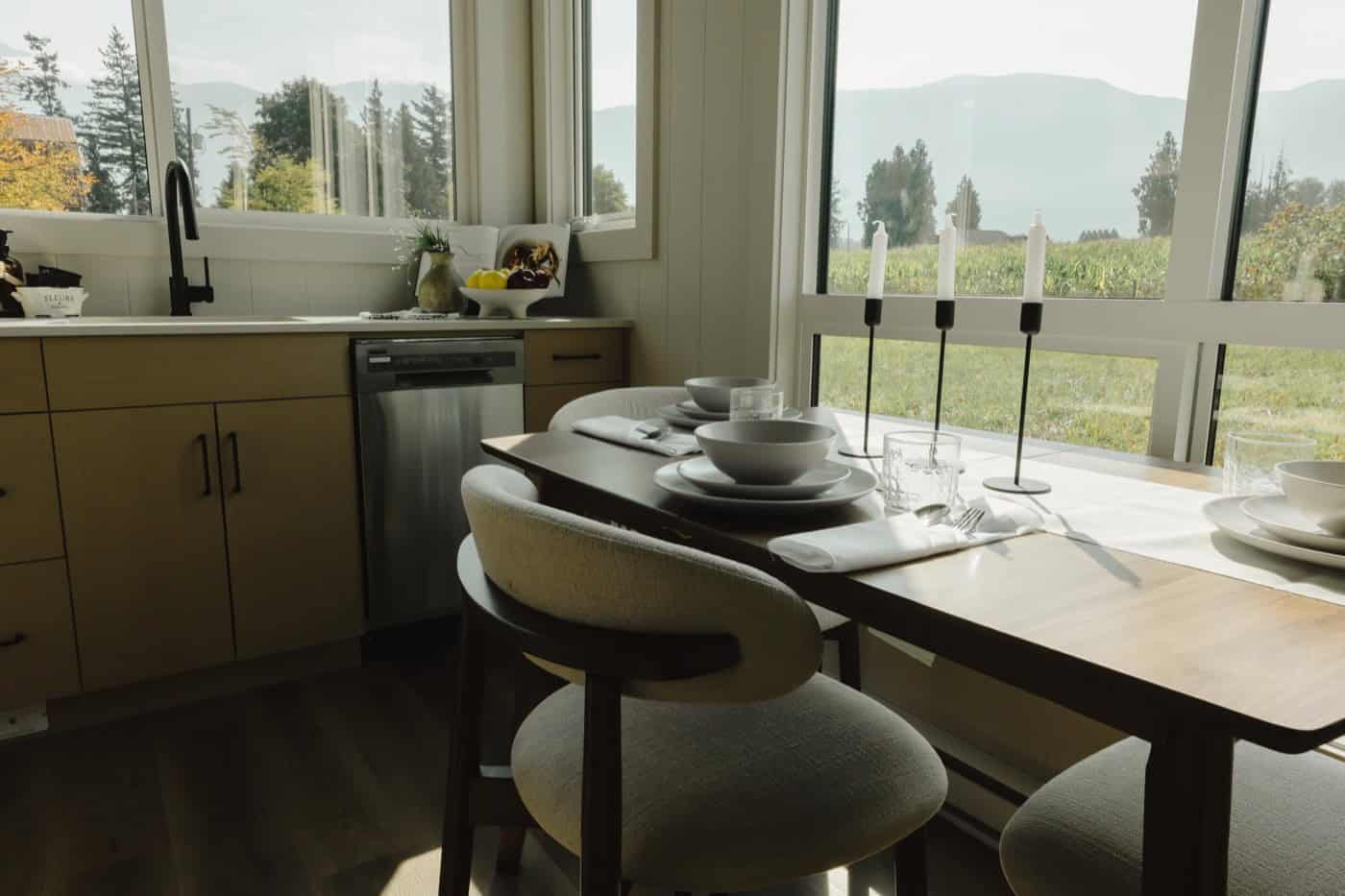 Dining table set for a meal beside floor-to-ceiling windows with mountain views in the Mint Ventura
