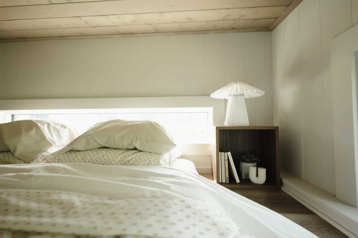 Queen bed in a sleeping loft of the Mint Ventura with a plank wood ceiling and clerestory window
