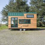 Tiny house on wheels with outdoor bar area and modern design.