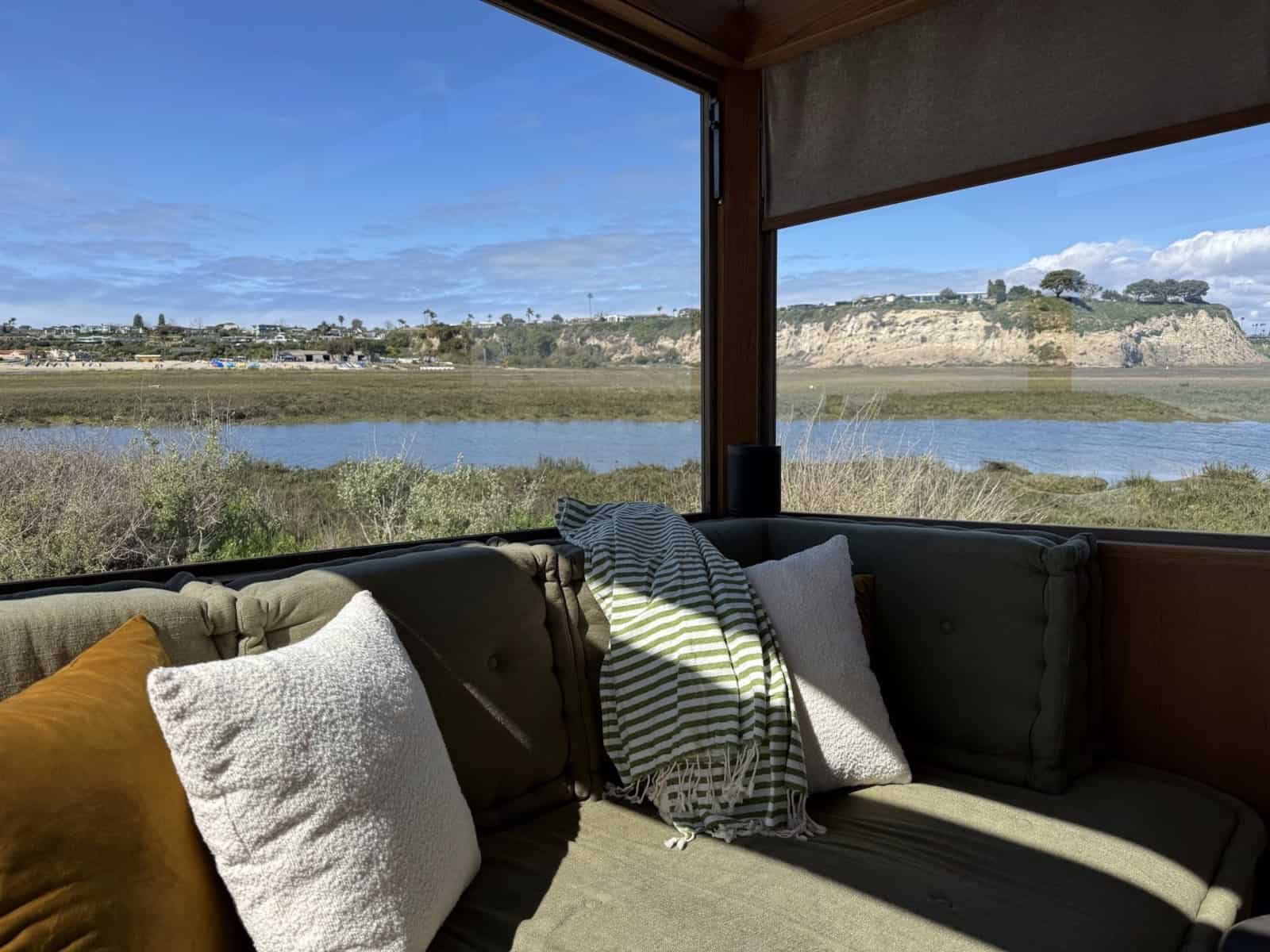 Daybed in the MoD tiny house facing a coastal estuary through wraparound glass