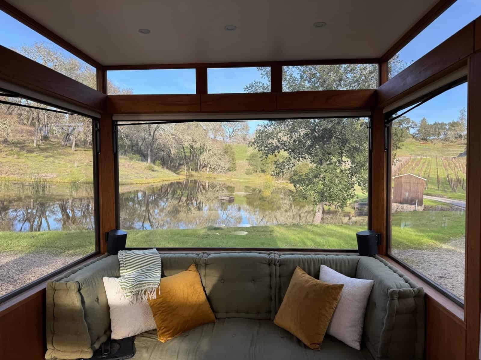 View from inside the MoD tiny house over the daybed to a pond and vineyard