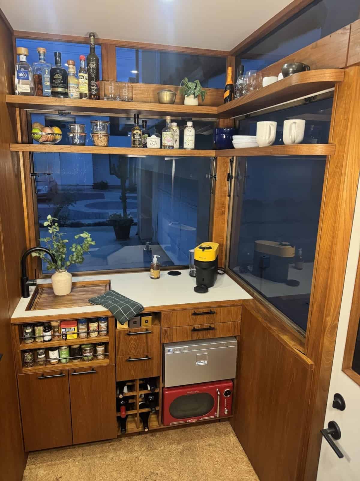 Teak kitchenette in the MoD tiny house with open shelving and window backsplash