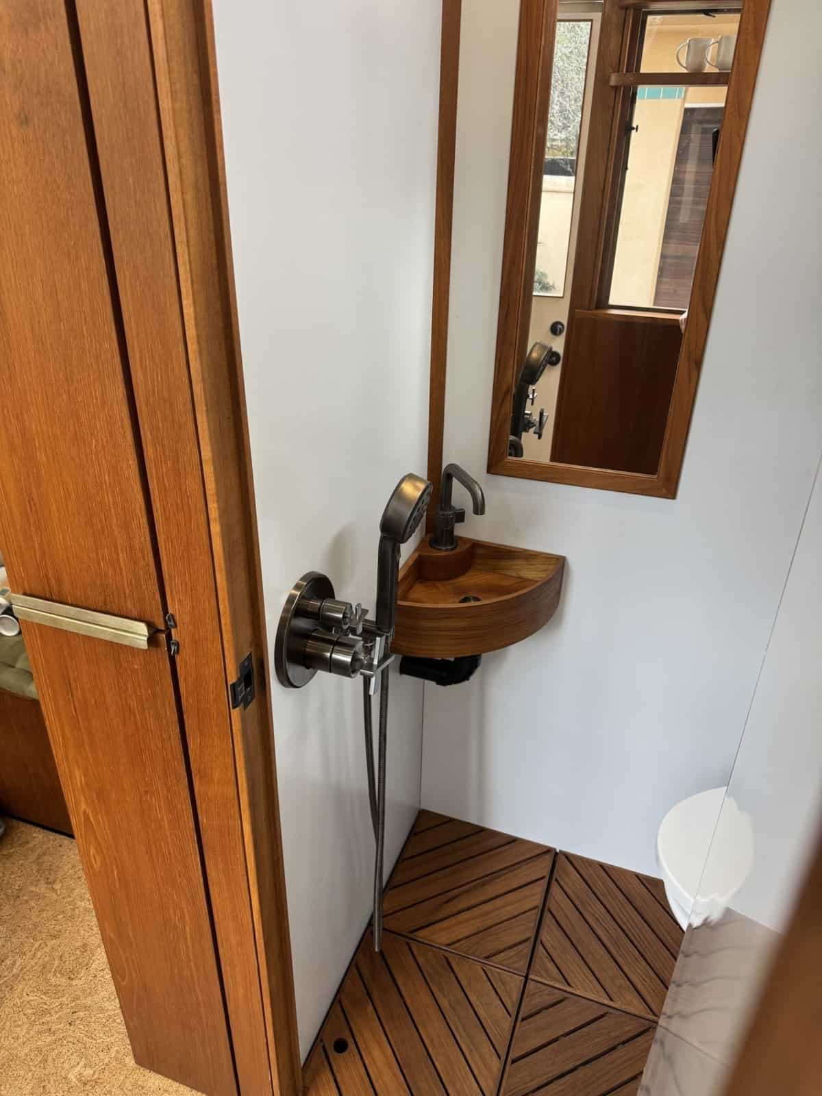 Wet room with teak slat floor, hand shower and corner teak sink