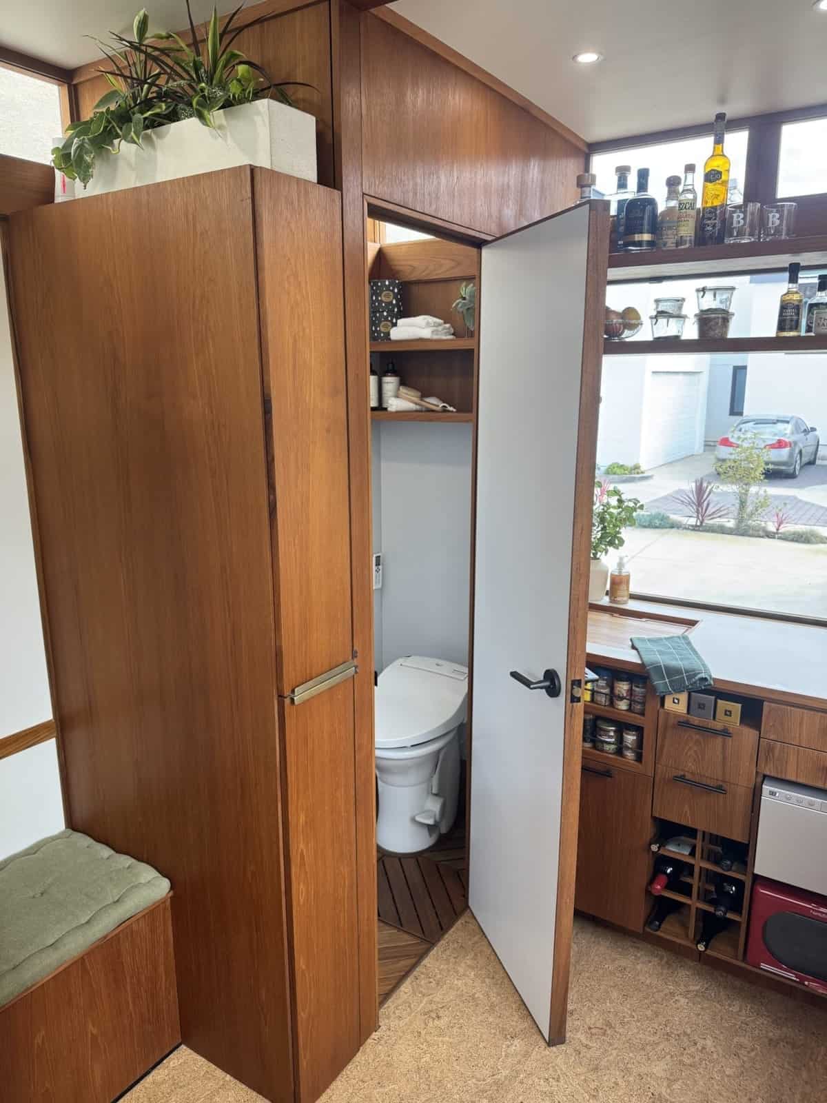 Teak door opening to the compact wet room in the MoD tiny house