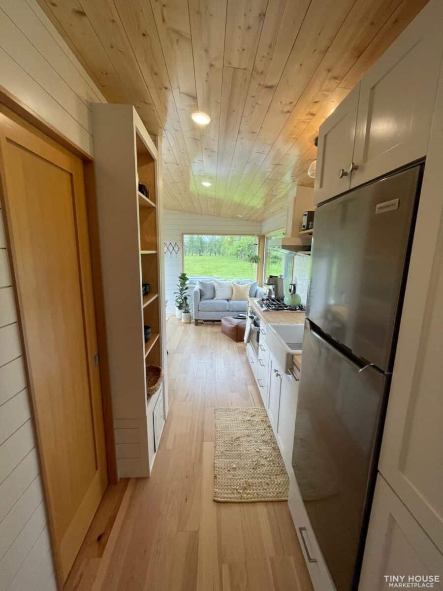 Bright, compact kitchen in a modern tiny house with natural wood accents and a view of the living sp.