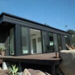Cozy tiny house with sleek black exterior, large glass doors, and mountain views in California.