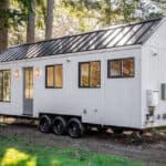 Compact modern cottage on wheels with sleek design and large windows for a cozy tiny home experience.