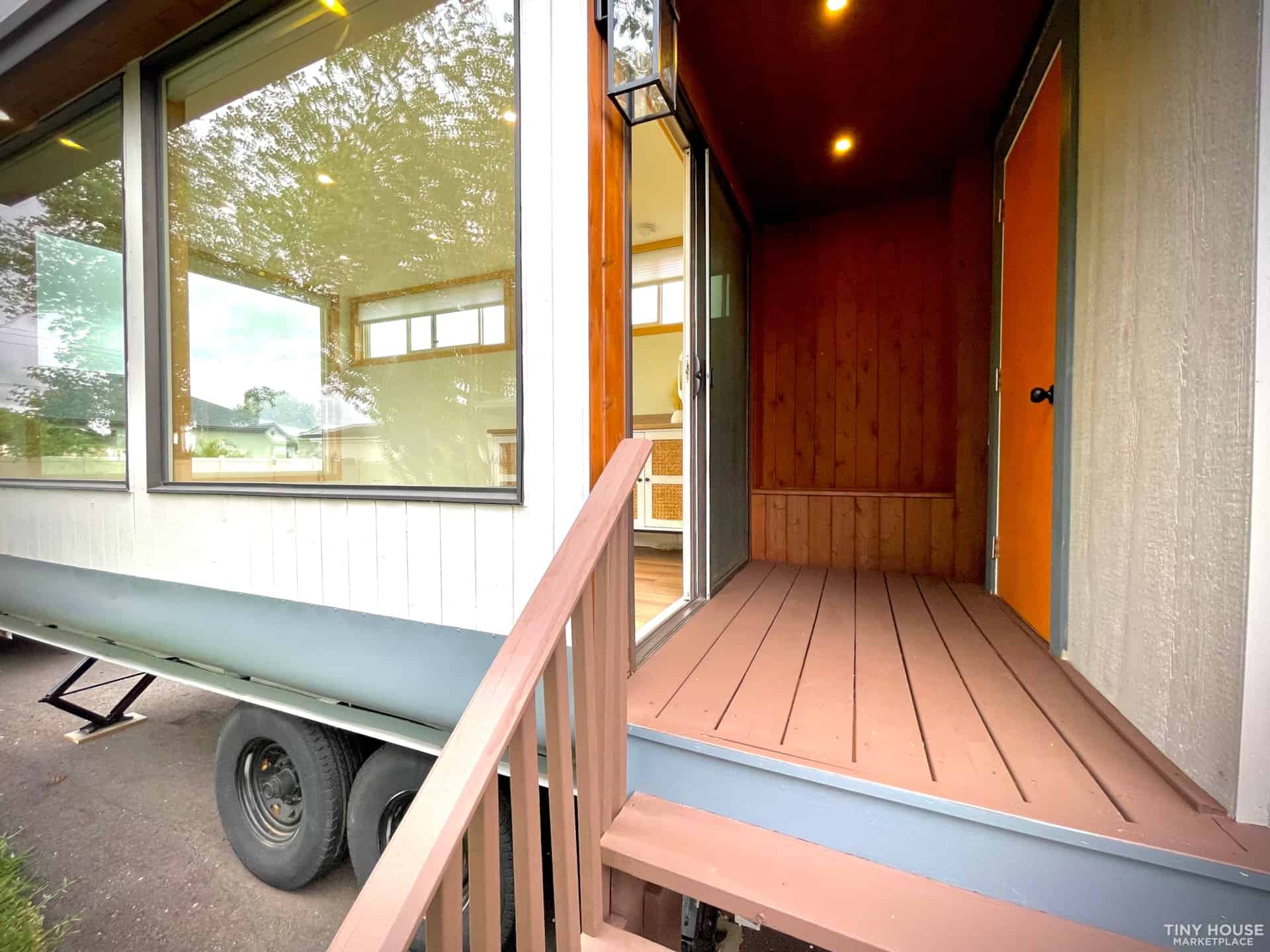 Charming tiny house porch with wooden flooring and warm lighting, perfect for small space living.