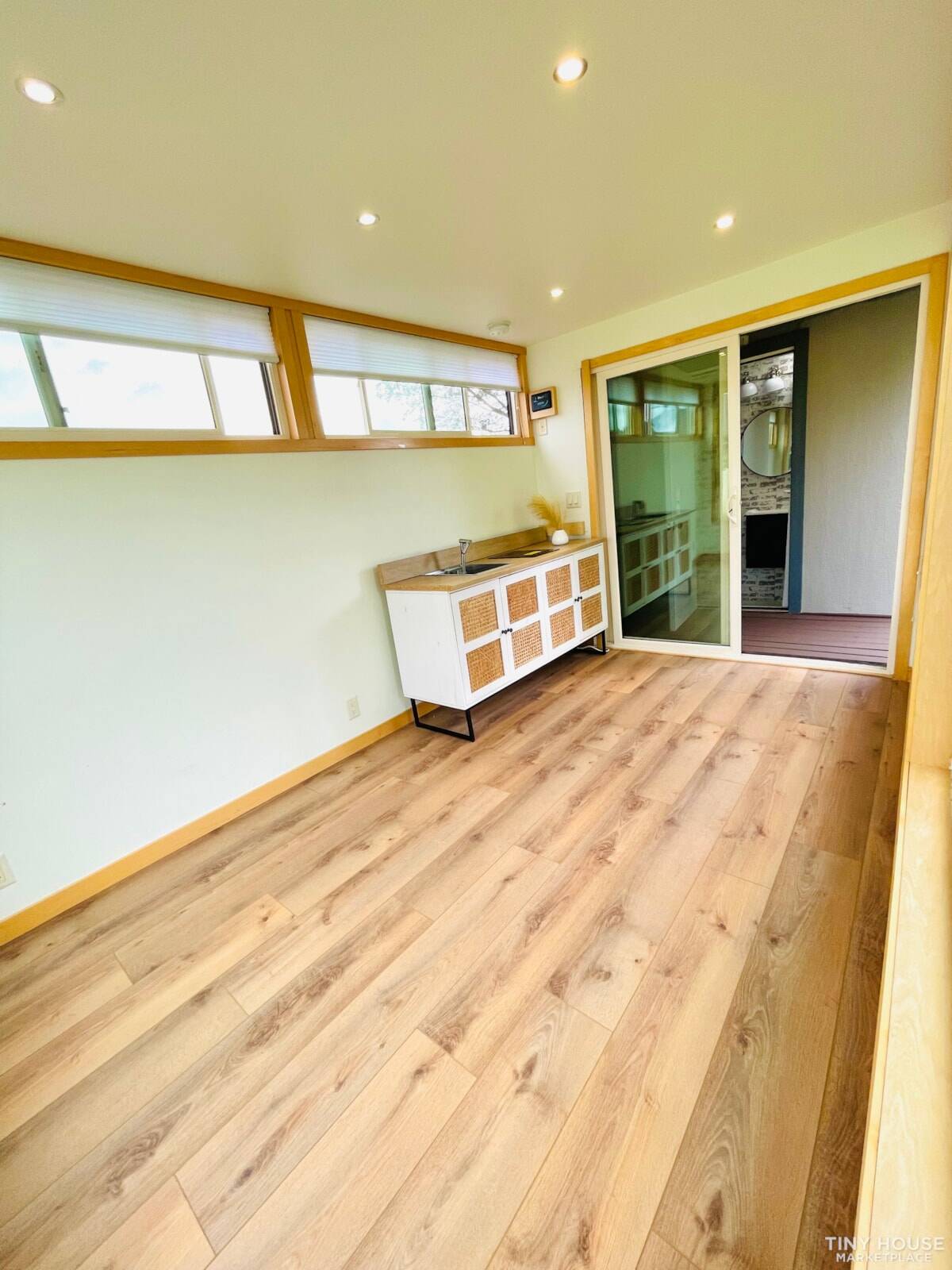 Compact kitchen area with white rattan-door cabinet, sink, and clerestory windows above