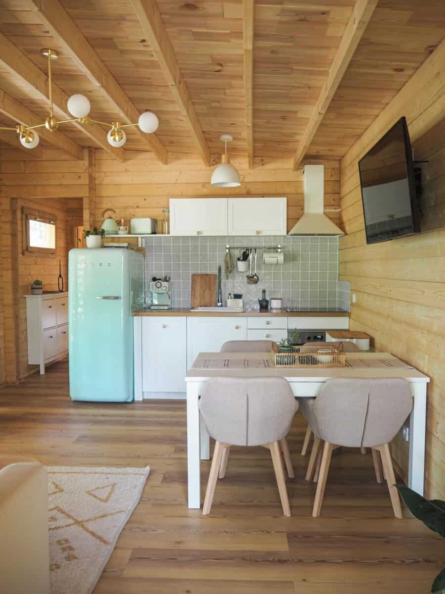 Bright wooden tiny house kitchen with modern appliances and dining area.