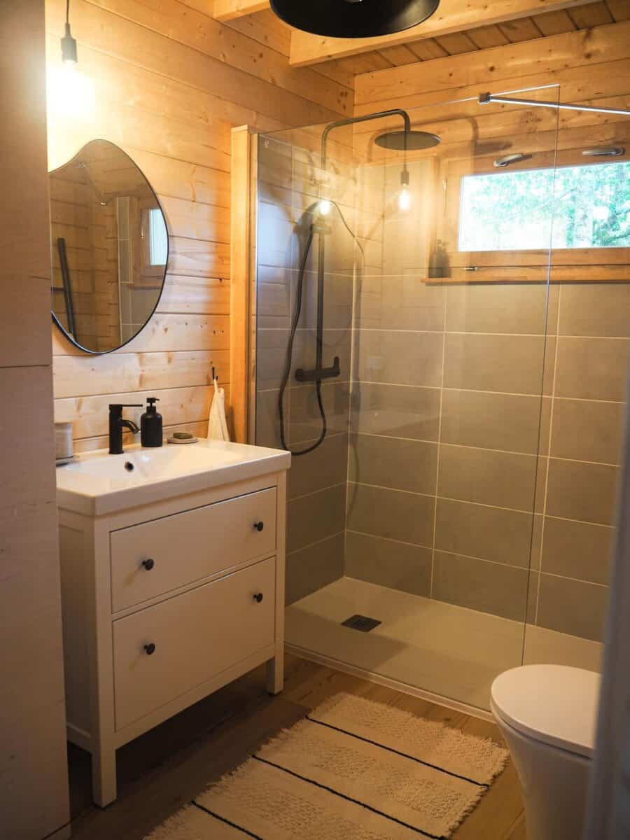 Modern wooden bathroom with walk-in shower and natural light.
