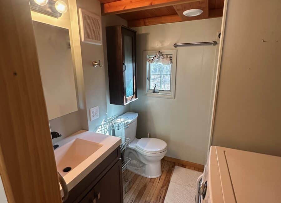 Compact tiny house bathroom with a sleek sink, toilet, and storage solutions.