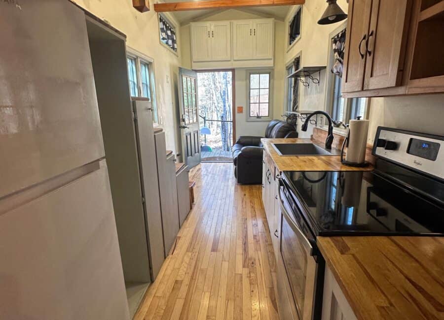 Compact tiny house kitchen with natural light and creekside scenery.