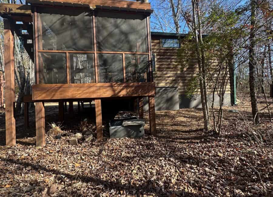 Charming tiny house elevated on stilts with screened porch and scenic creekside surroundings.
