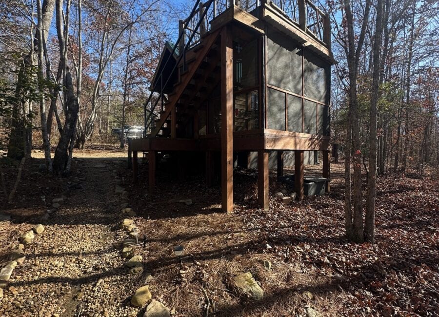 Tiny house with rooftop deck overlooking a wooded creekside setting.
