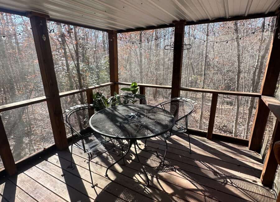 Cozy creekside deck with outdoor table and chairs in a tiny house setting.