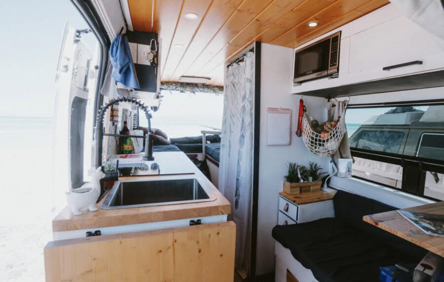 Compact tiny house kitchen and living space with ocean scenery outside.