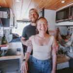 Happy couple inside a tiny house van conversion, showcasing small space living.