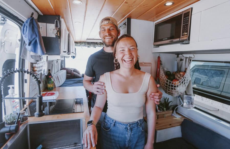 Happy couple inside a tiny house van conversion, showcasing small space living.