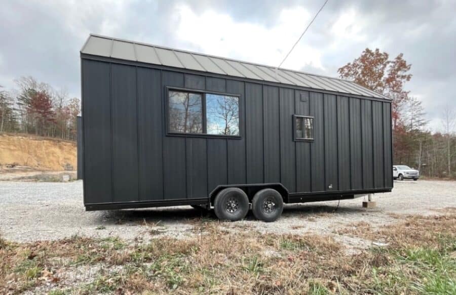 Modern black tiny home on wheels with large windows.