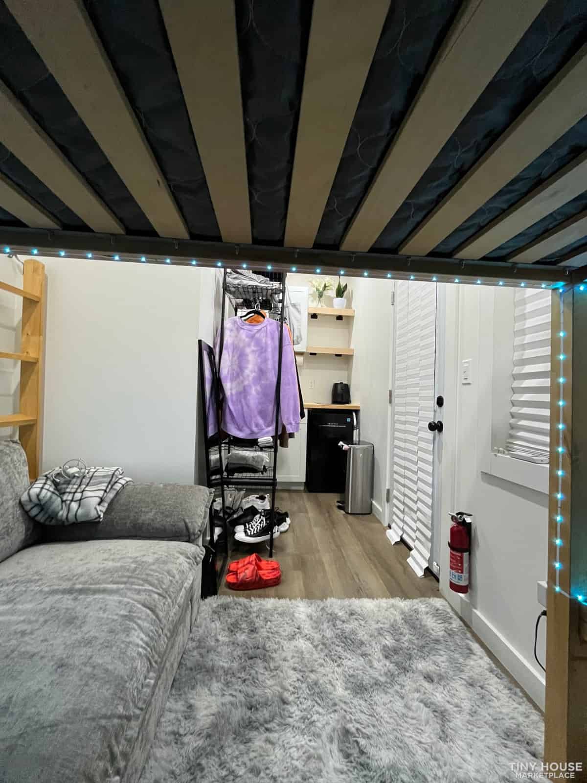 Compact tiny house bedroom with loft and storage solutions.