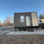 Portable tiny house with a small porch and single door, ideal for minimalist living.