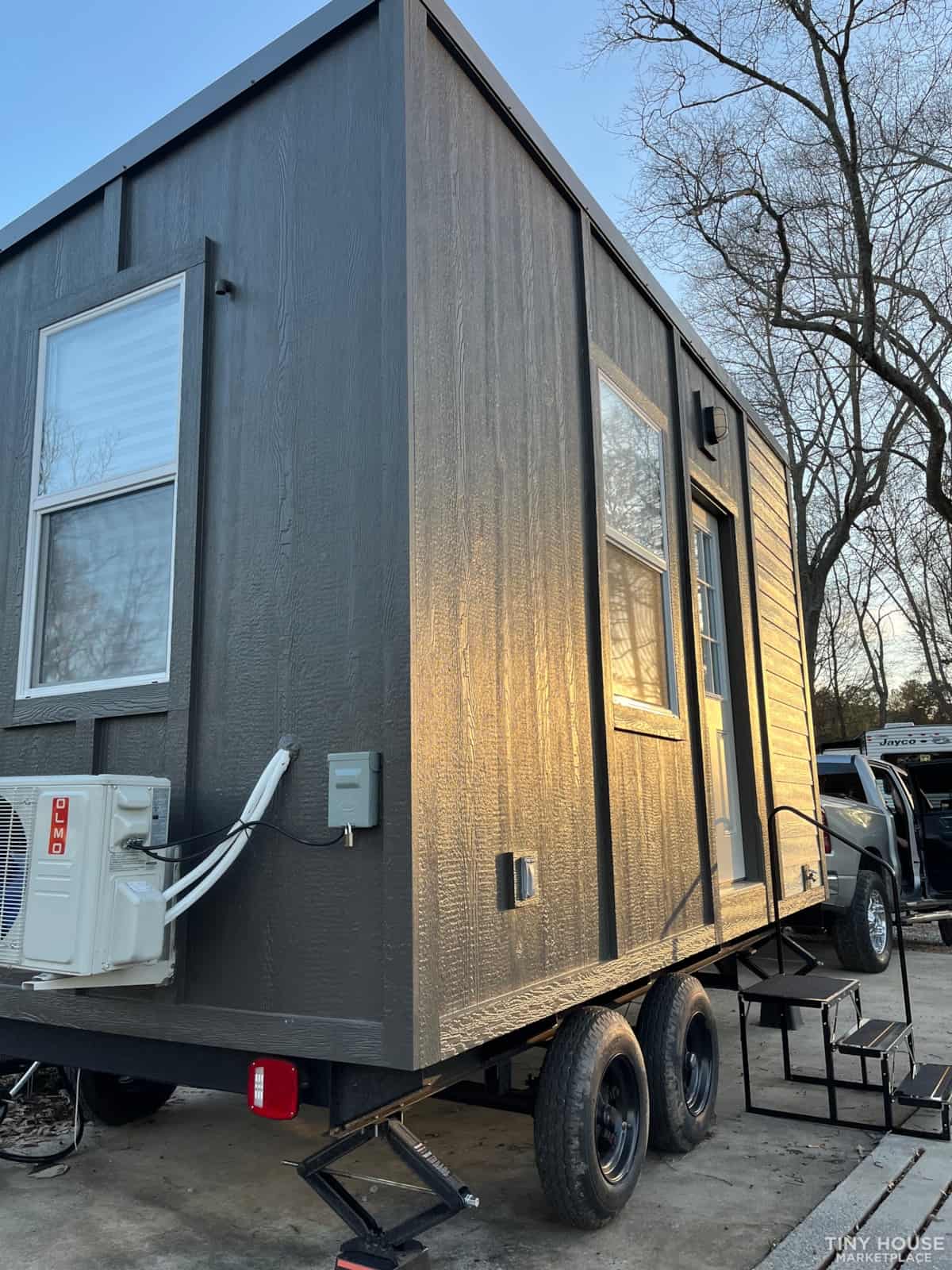 Mobile tiny house with modern design and large windows.