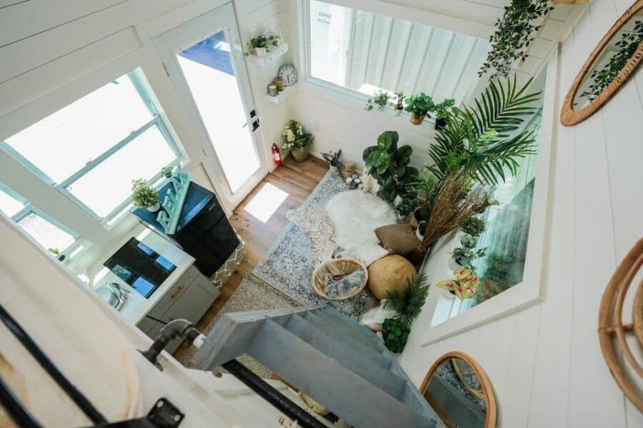 Cozy tiny house living space with abundant natural light and lush greenery.