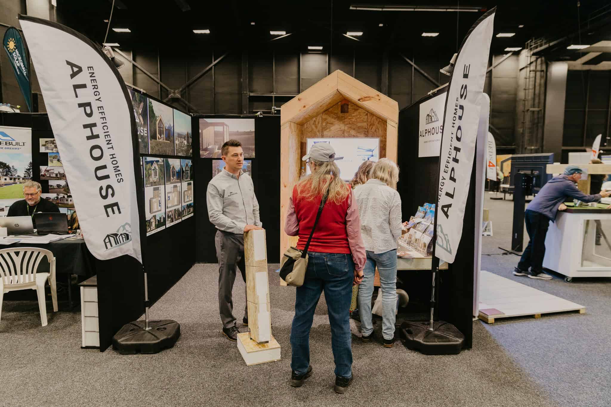Exhibitor stand with a timber frame wall cutaway and energy efficient home displays at the expo