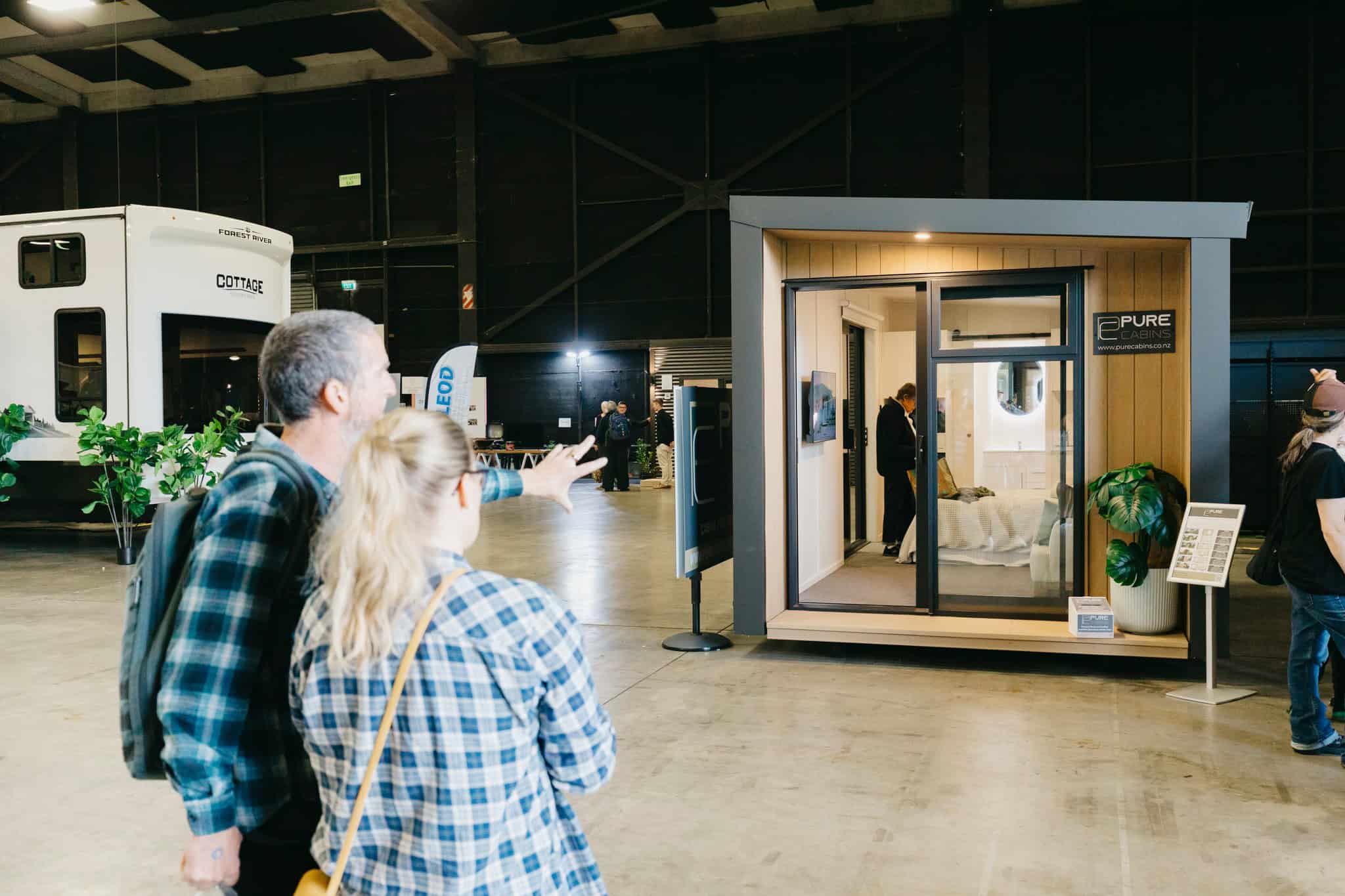 Attendees looking at a compact cabin display unit with sliding glass doors inside the expo hall