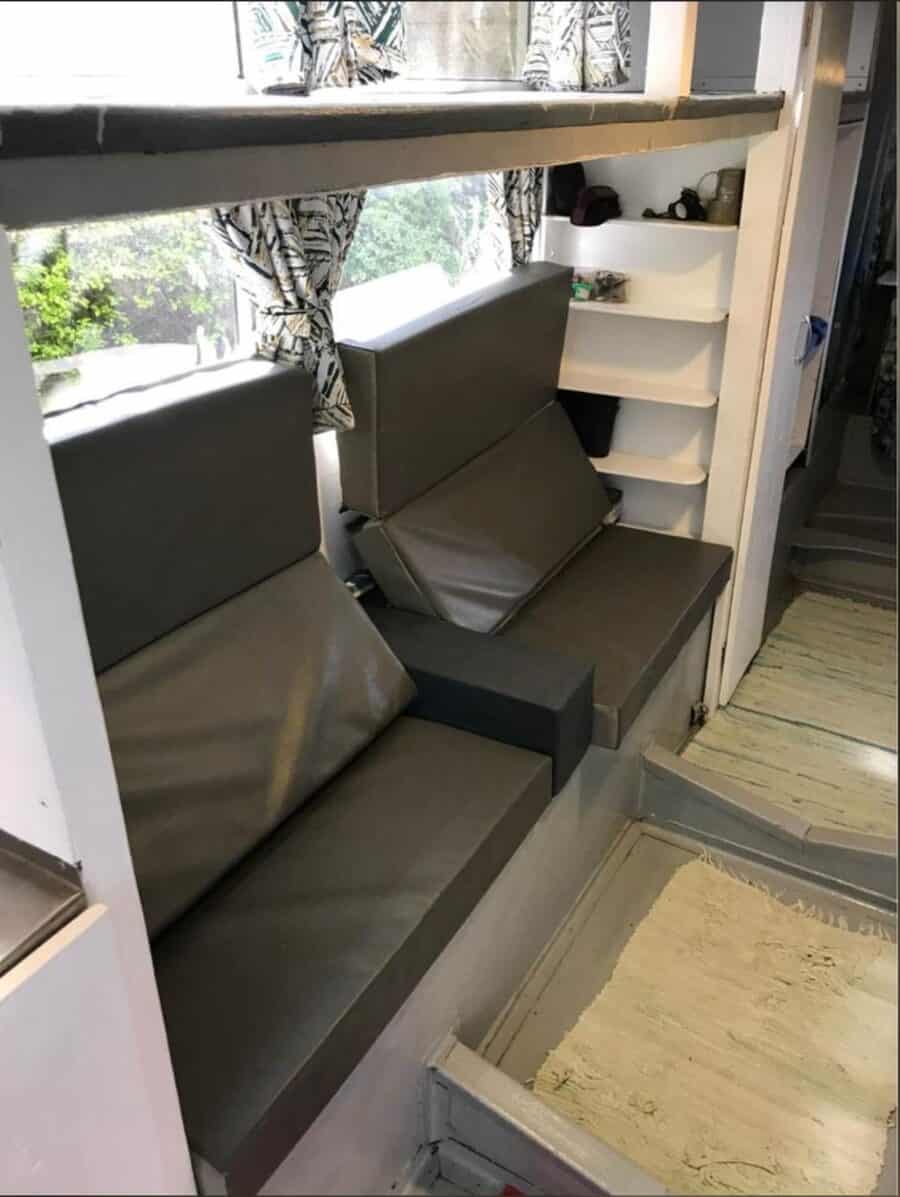 Seating area inside a tiny house with compact, modern cushions and built-in shelves for storage.
