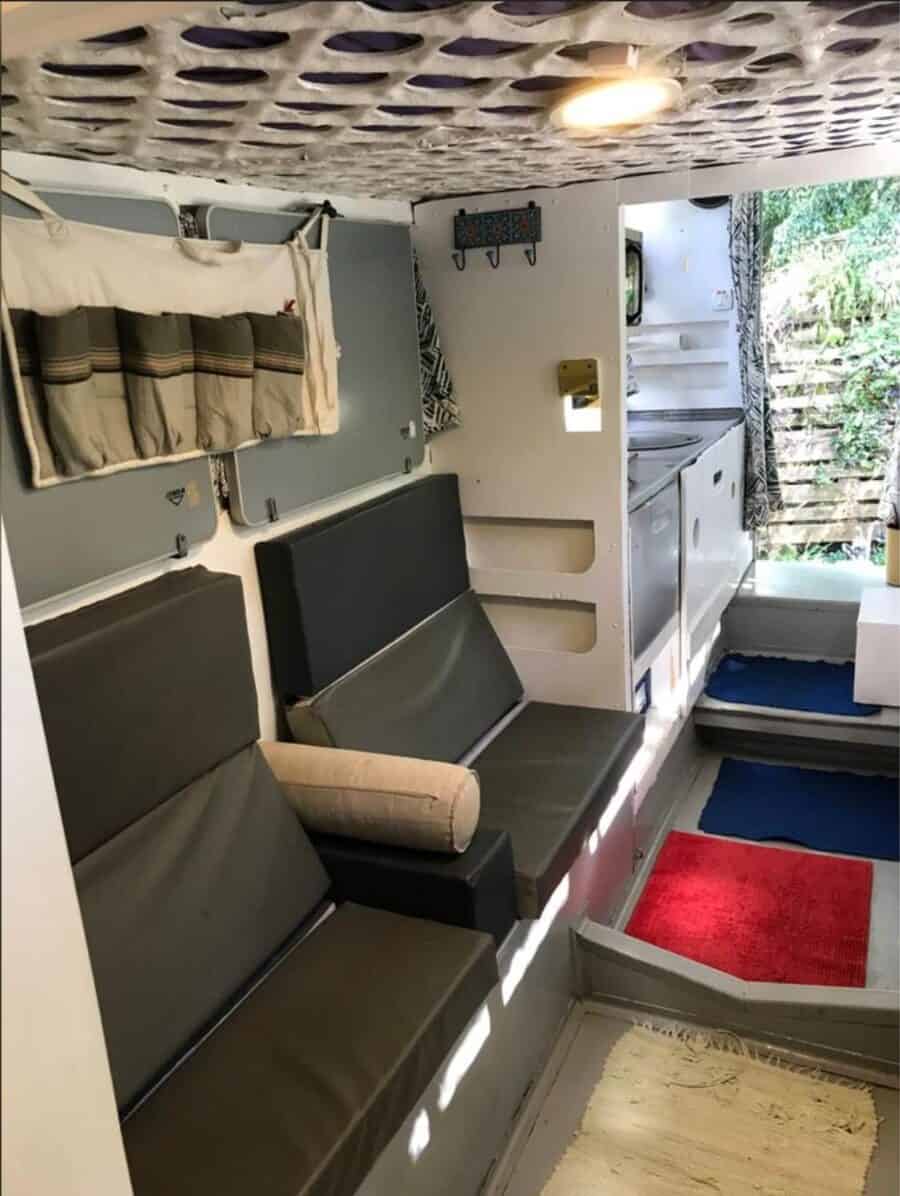 Compact tiny house interior with seating, kitchenette, and loft for sale.