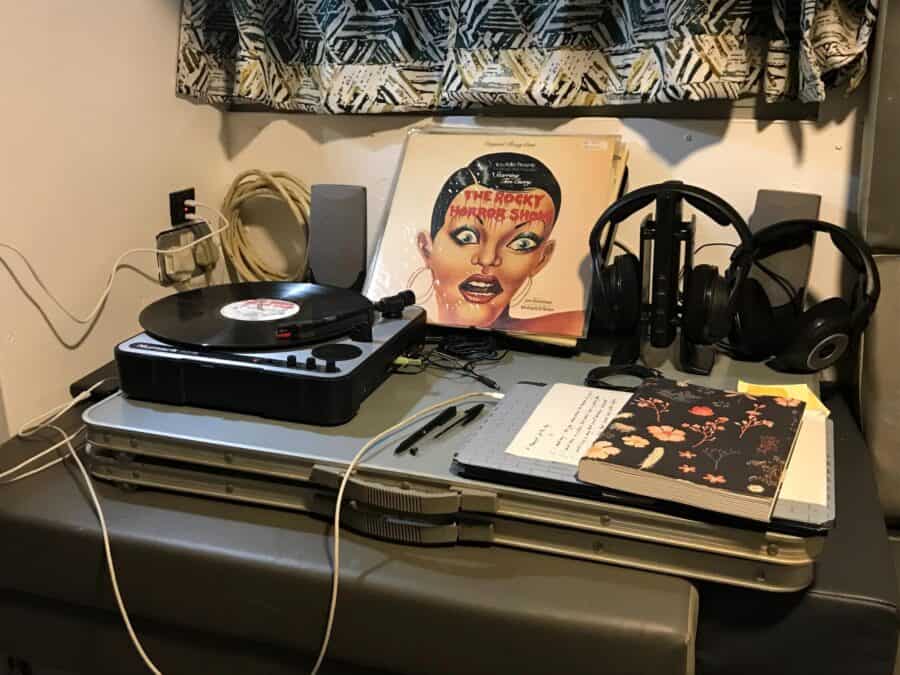 Compact tiny house entertainment area with record player, headphones, and vintage album.