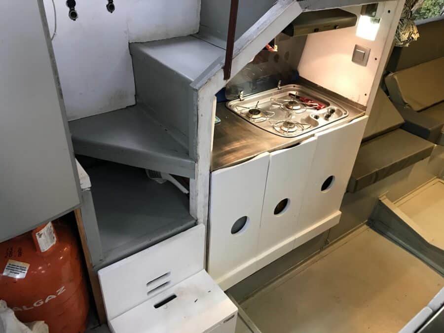 Compact tiny house kitchen with stove and storage under a loft.