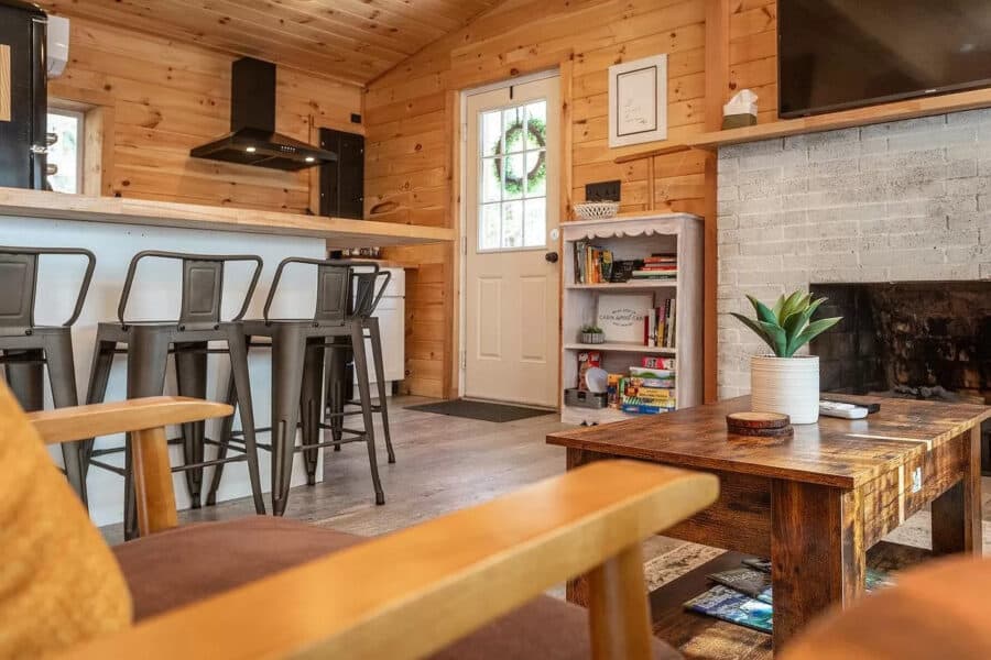 Charming tiny house interior featuring wood-paneled walls, a compact kitchen, and inviting living sp.