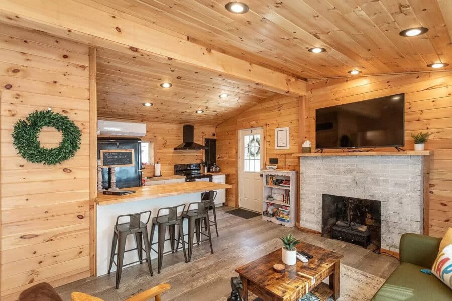 Charming tiny house interior with wood paneling, modern kitchen, and comfortable living space in a f.