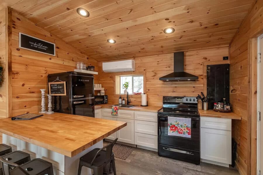Charming tiny house kitchen with wood accents, modern appliances, and efficient layout for small spa.