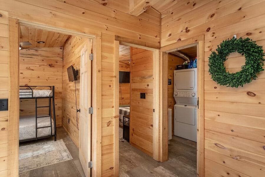 Charming tiny house interior with wood paneling, compact laundry area, and cozy bedrooms.