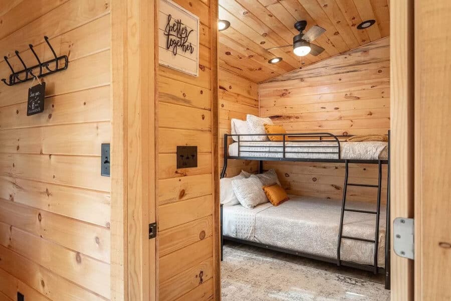 Small wooden cabin bedroom with bunk beds and rustic decor.
